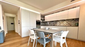 A modern kitchen with white cabinets, a patterned backsplash, and a dining area with a table and chairs. - Large, bright and modern flat with an incredible view on lake Garda in Malcesine (Malcesine)