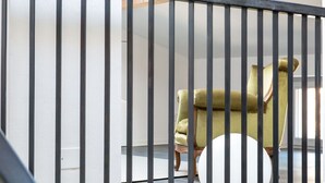 A room with a black metal railing, a green upholstered chair, and a white round table.