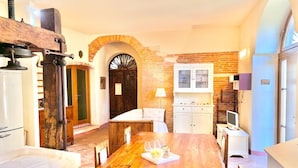 Um quarto aconchegante com mesa de jantar de madeira, móveis brancos, parede de tijolos e porta de madeira.