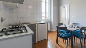 Une cuisine moderne équipée d’une cuisinière à gaz, d’un évier et d’un lave-vaisselle compact. On y trouve également un coin repas avec une table et des chaises, ainsi qu’une fenêtre qui laisse entrer la lumière naturelle.