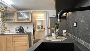 A modern kitchen with wooden cabinets, a black countertop, and a sink. There is a potted plant on the countertop and a microwave above it. - Lovely apartment for 4 guests with WIFI, A/C, TV and patio (Costarainera)