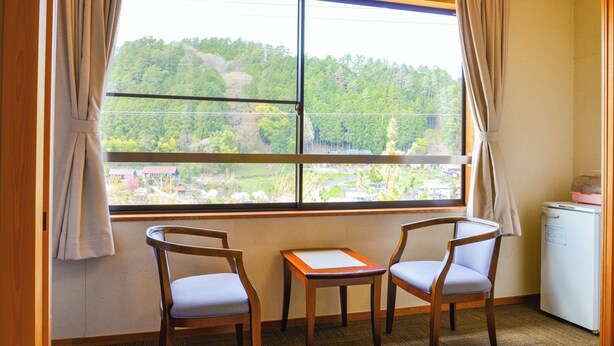A room with a large window, two wooden chairs, a small table, and a white refrigerator. - Okutenryu Fudouonsen Sawaya (Iida)