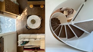 Un intérieur moderne avec une table de salle à manger ronde, un canapé et un escalier en colimaçon.