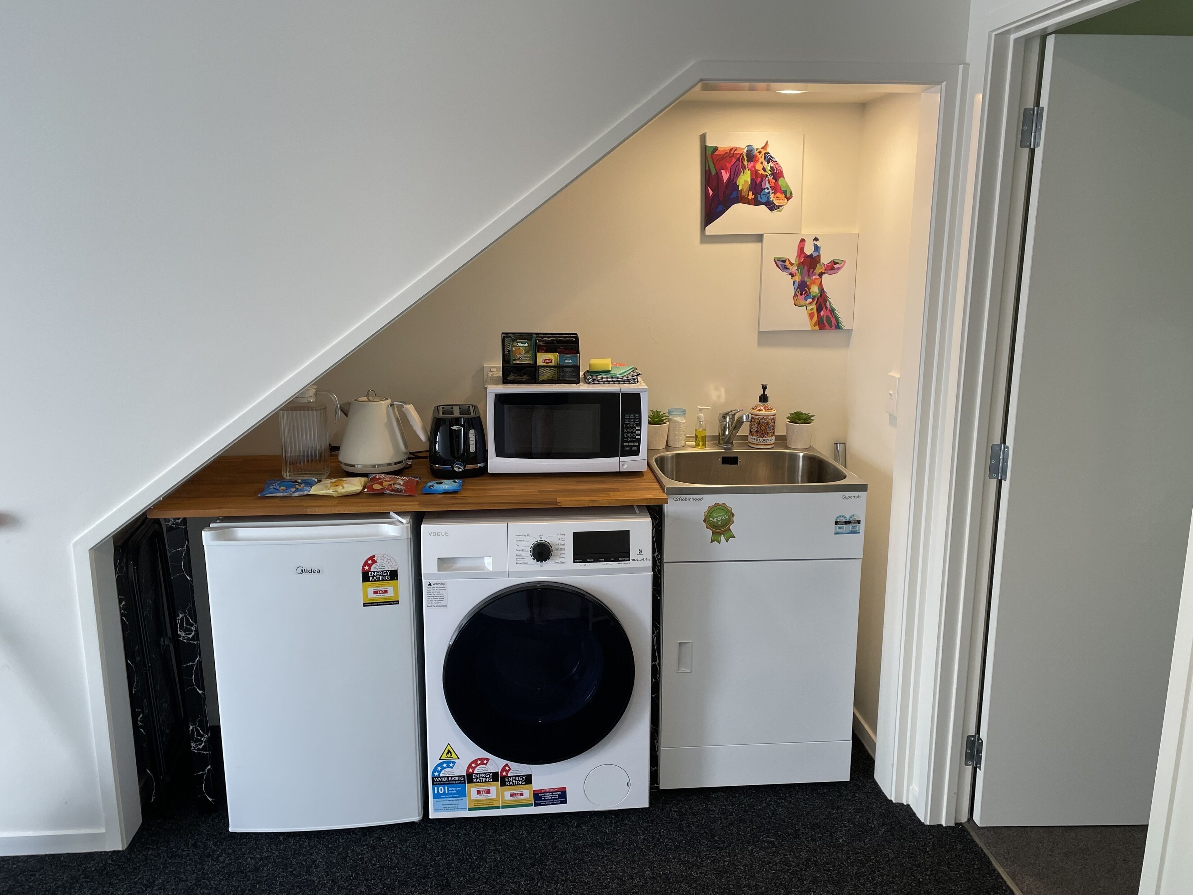 Eine kleine Küchenzeile mit Mikrowelle, Toaster, Wasserkocher und Spüle.