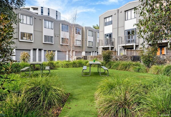 A modern apartment complex with a well-maintained lawn and picnic tables.