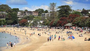 A crowded beach with people, tents, and buildings in the background. - Auckland City Private-Modern Downstairs Ensuite+Patio+secluded Garage in Parnell (Auckland)
