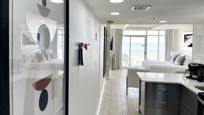 A modern hotel room with a large bed, a kitchenette, and a balcony with a view of the sea. - Oceanfront - Couples Modern Miami Inspired (Myrtle Beach)