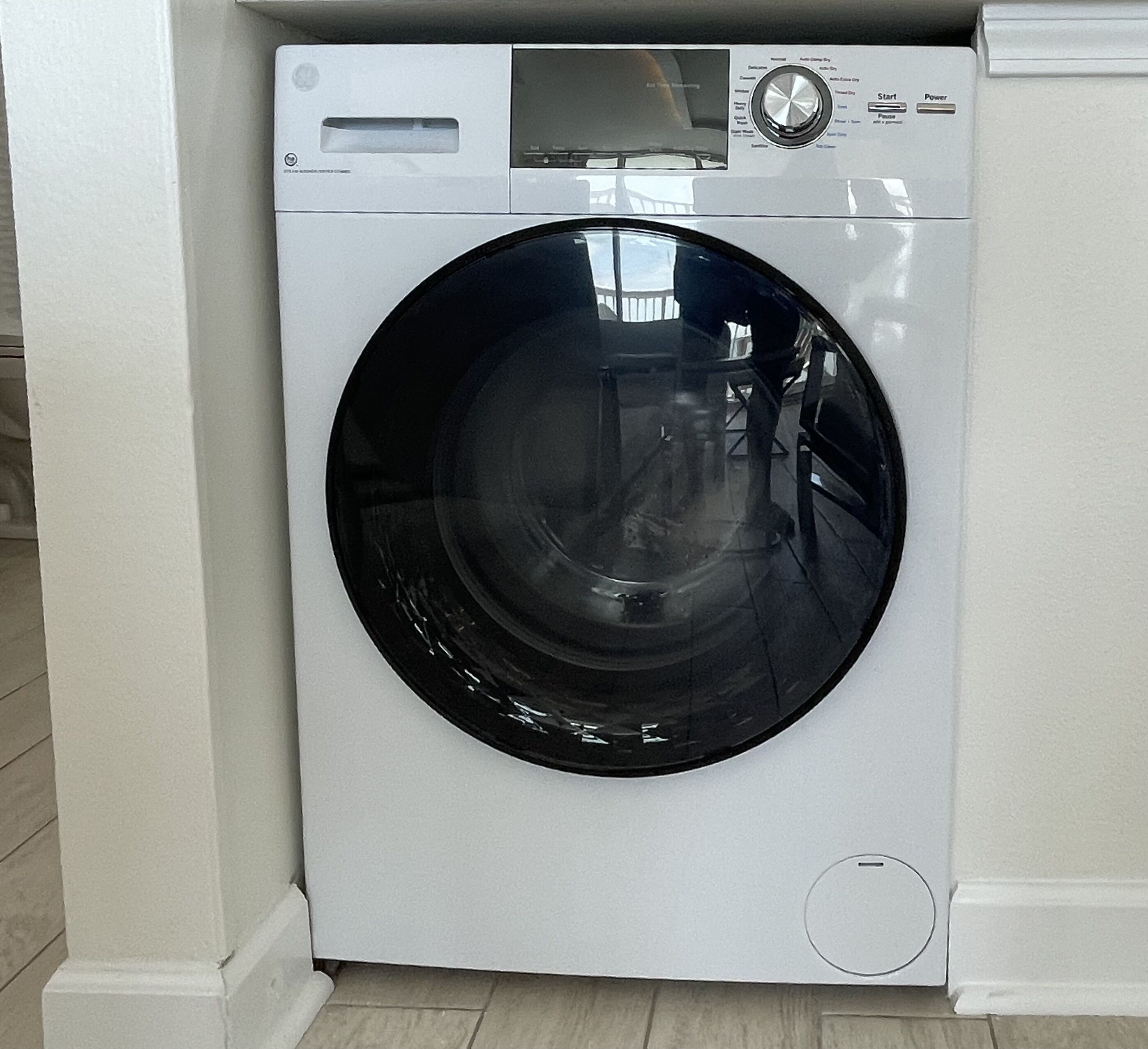 A front view of a white front-loading washing machine with a digital display and control panel.