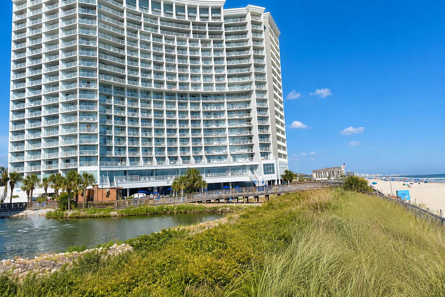 A large, multi-story hotel with a curved facade, located near a beach and a body of water. - Oceanfront - Couples Modern Miami Inspired (Myrtle Beach)