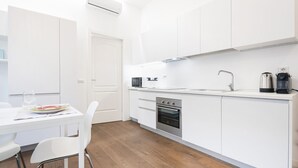 Una cocina moderna con armarios blancos, microondas, cafetera y horno.