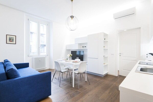 Eine moderne, gut beleuchtete Wohnung mit Essbereich, Küchenzeile und einem blauen Sofa.