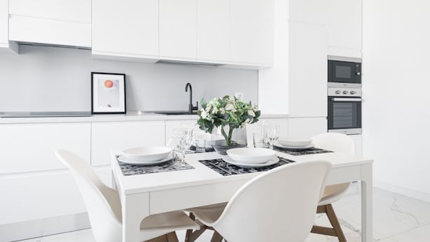 A modern kitchen with white cabinetry, a dining table set with plates and glasses, and a vase with flowers. - Easylife - Spectacular flat in Citta Studi (Milano)