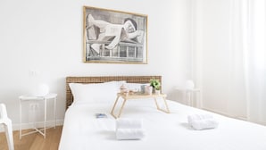 A modern hotel room with a large bed, a bedside table, a small side table, a bedside lamp, a wall-mounted painting, and a window with curtains. - Easylife - Spectacular flat in Citta Studi (Milano)