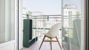 A balcony with a white chair, a small table with a glass, and a green plant. - Easylife - Spectacular flat in Citta Studi (Milano)