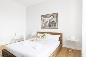 Une chambre d’hôtel moderne avec un grand lit, une table de chevet, une chaise et une œuvre d’art accrochée au mur.