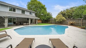 En baghave med swimmingpool, overdækket terrasse og træterrasse.