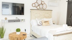 Een slaapkamer met een bed, een tv aan de muur, een houten salontafel en een airconditioner.