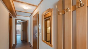 Un couloir avec des portes en bois et un luminaire au plafond.
