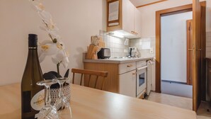 Une cuisine avec une table en bois, une bouteille de vin et un vase orné d’orchidées.