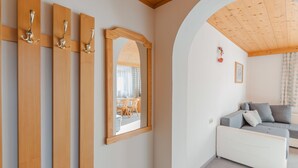 Une pièce avec un plafond en bois, un canapé blanc, un miroir et une porte en bois dotée de trois poignées.