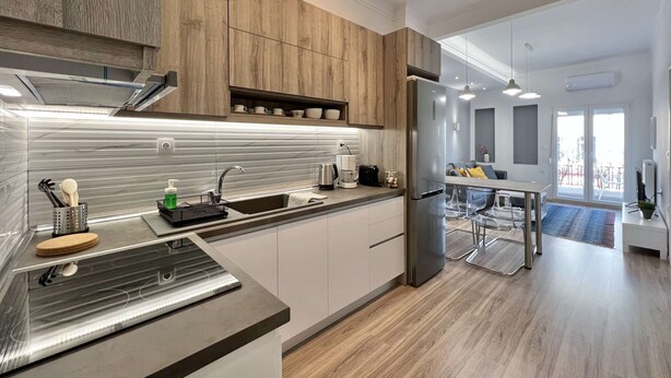 A modern kitchen with a stainless steel sink, wooden cabinets, and a built-in oven. - Liberty: Vibrant family apartment (Thessaloniki)