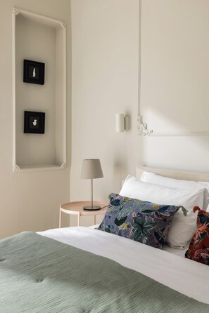 A neatly arranged bedroom with a bed, pillows, a lamp, and two wall-mounted picture frames. - Liberty by halu! | 3 Bedroom Apartment in Thessaloniki Center (Thessaloniki)