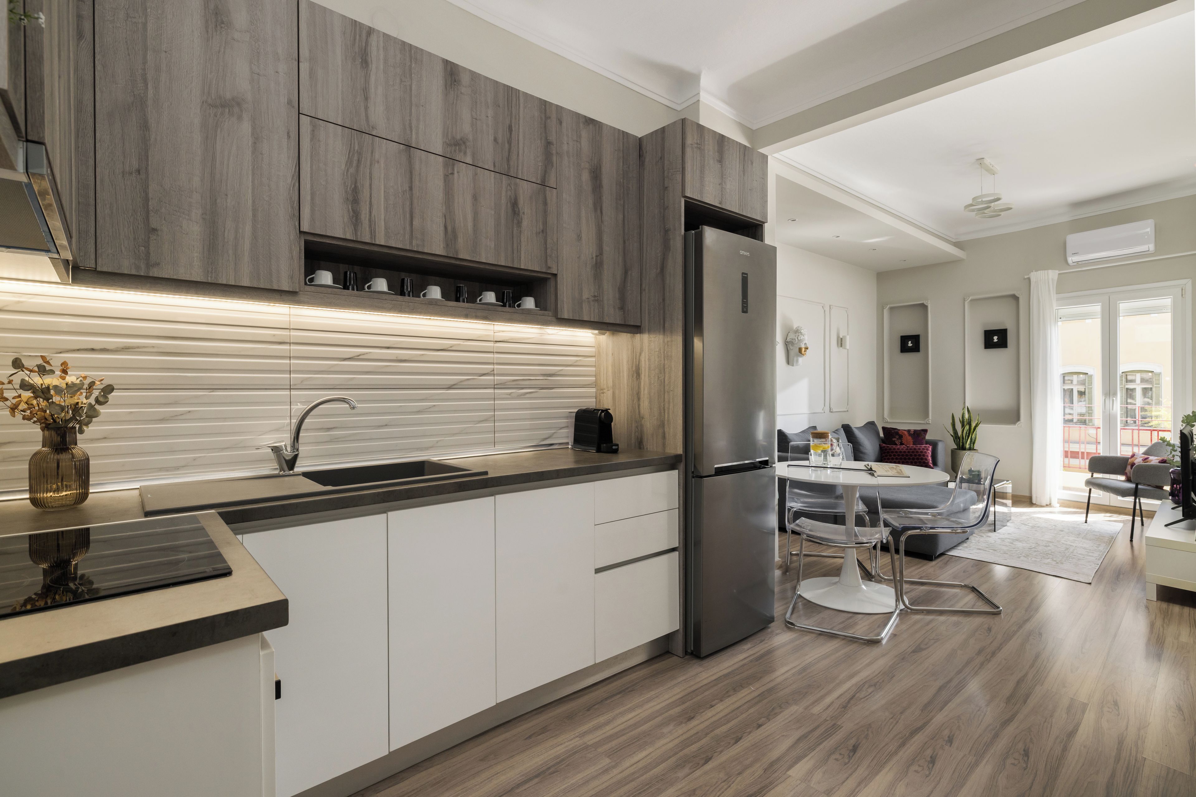 A modern kitchen with a built-in oven, a stainless steel refrigerator, and a wooden backsplash.
