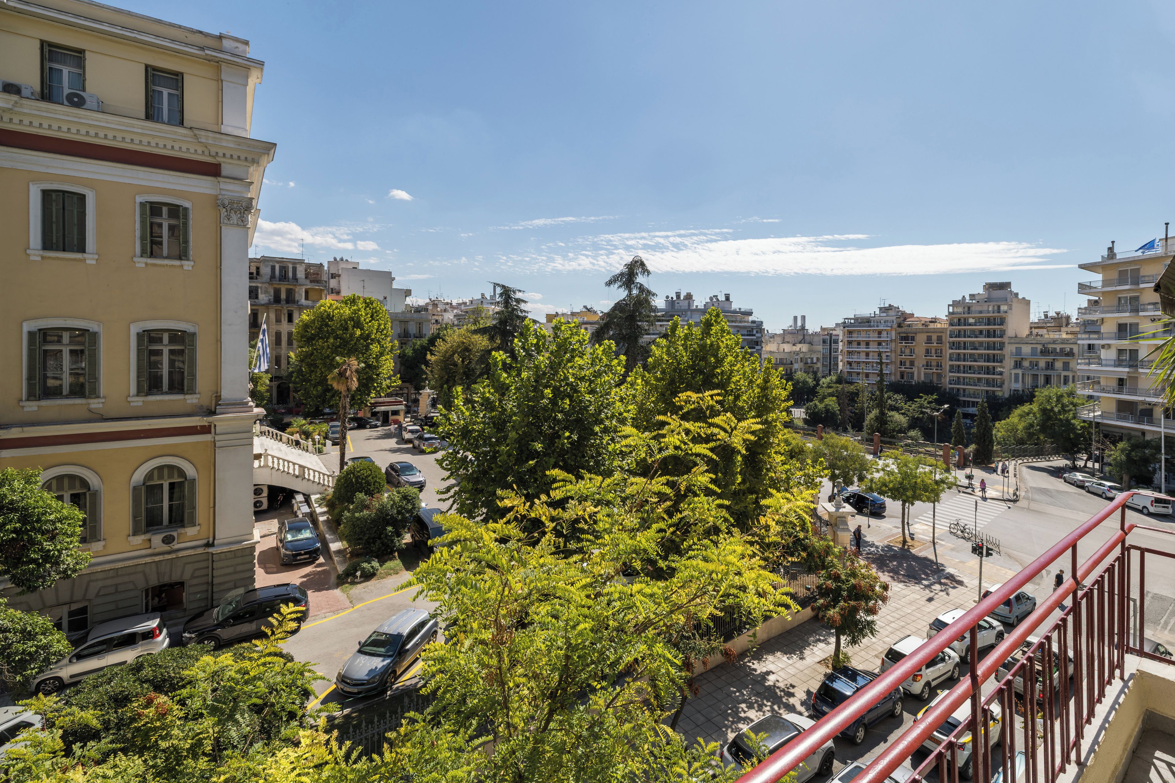 A cityscape with buildings, trees, and parked cars.