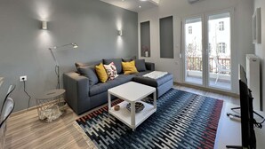 A modern living room with a grey sofa, white coffee table, and patterned rug. - Liberty: Vibrant family apartment (Thessaloniki)
