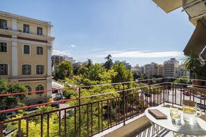 A balcony with a table, a chair, and a potted plant. - Liberty by halu! | 3 Bedroom Apartment in Thessaloniki Center (Thessaloniki)