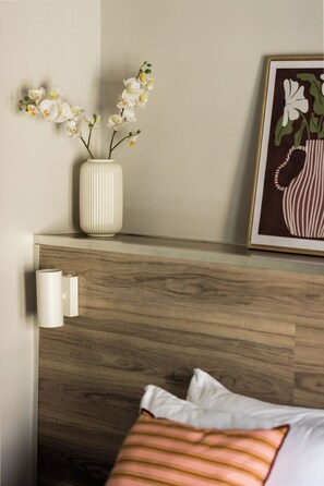 A bedroom with a wooden headboard, a white vase with flowers, a framed picture, and a bedside lamp. - Liberty by halu! | 3 Bedroom Apartment in Thessaloniki Center (Thessaloniki)