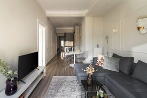 Una sala de estar moderna con un televisor de pantalla plana, un sofá gris, una mesa de centro y un jarrón decorativo.