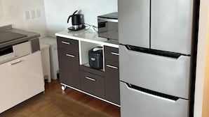 A modern kitchen with a stainless steel refrigerator, a coffee maker, and a dishwasher. - Bigstone Terrace Suite Tsutsumimachi (Aomori)