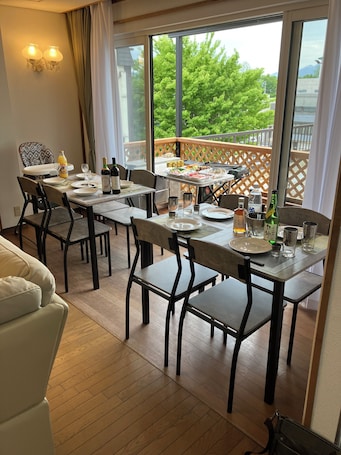 A dining area with a table set for four, a sofa, and a view of a balcony with a wooden fence.