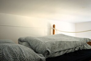 A room with a bed, a wooden post, and a rope tied to it. - Le Joffre - Studio sur la Digue en Centre Ville (Arromanches-les-Bains)