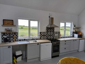 A kitchen with a view of the countryside, a stove, a microwave, and a dishwasher.