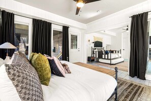 Un dormitorio con una cama grande, un escritorio y una silla, una ventana con cortinas y vistas al exterior.