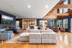 Una sala de estar moderna con chimenea, un sofá modular y un televisor grande.