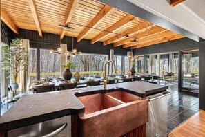 A modern kitchen with a copper sink, wooden ceiling beams, and large windows. - 7k sq ft Mountain Estate -The Most Epic Experience (Asheville)