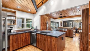 Een moderne keuken met houten kastjes, een centraal eiland en een eetgedeelte met uitzicht.