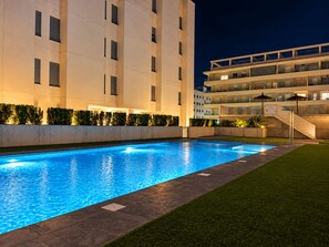 A swimming pool with a clear blue water surface, surrounded by a paved deck and a well-maintained grassy area. - New apt. at the beach of Daimus - near Gandia (Daimús)