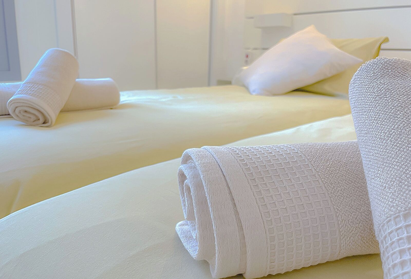 Habitación de hotel con dos camas, cada una con ropa blanca y almohadas.