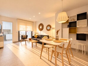 A modern living space with a dining area, sofa, and kitchen. - New apt. at the beach of Daimus - near Gandia (Daimús)