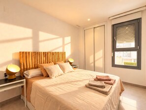 Une chambre moderne avec un grand lit, des lampes de chevet, une armoire et une fenêtre avec des stores.