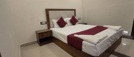 A neatly made bed with a wooden headboard, two nightstands, and a red and white patterned bedspread.