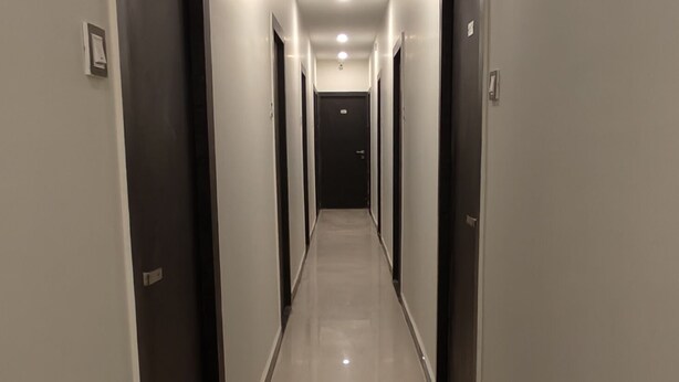Un pasillo largo y estrecho con puertas a ambos lados, que conduce a habitaciones individuales.
