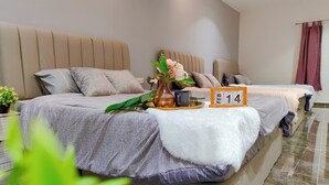 A hotel room with two beds, a wooden headboard, a small table with a vase and a mug, and a calendar displaying February 14.