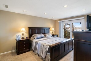 A bedroom with a bed, two bedside tables with lamps, a dresser, and a window with a view.