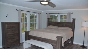 Une chambre à coucher avec un lit en bois, un banc, une commode et un ventilateur de plafond.