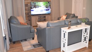 Un salon avec un canapé gris, une table basse blanche et un téléviseur à écran plat posé sur un meuble en bois.